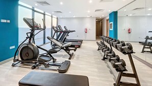 Une salle de sport moderne équipée de machines de cardio, d’haltères et d’un banc de musculation.