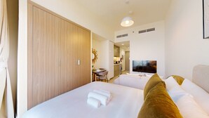 Une chambre d’hôtel avec deux lits, une télévision, un bureau et un miroir.