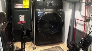 Un lavadero pequeño con lavadora y secadora de carga frontal, un calentador de agua y un armario de servicios.