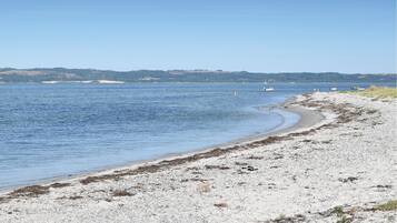Une plage au rivage de galets et aux eaux calmes.