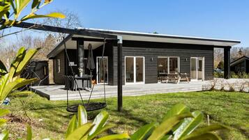 Une maison moderne dotée d’un patio, d’une balançoire et d’un coin repas.