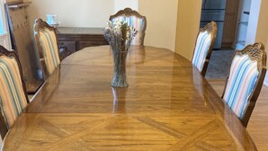 A dining table with six chairs, a vase with dried flowers, and a kitchen in the background. - ENTIRE Big Family Home Close To Zoo and Events - Private Patio and Firepit (Pittsburgh)