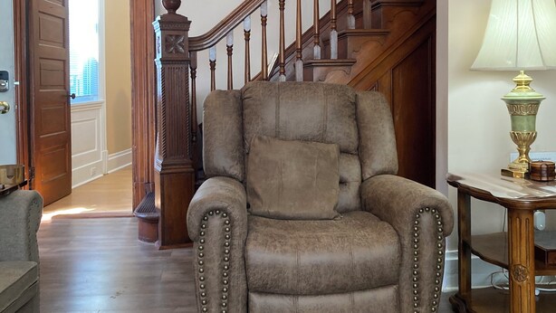 A spacious living room with a large armchair, a wooden staircase, and a lamp on a side table. - ENTIRE Big Family Home Close To Zoo and Events - Private Patio and Firepit (Pittsburgh)