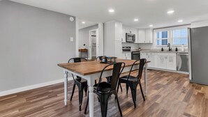 Una cocina moderna con armarios blancos, una mesa de comedor de madera y sillas negras.
