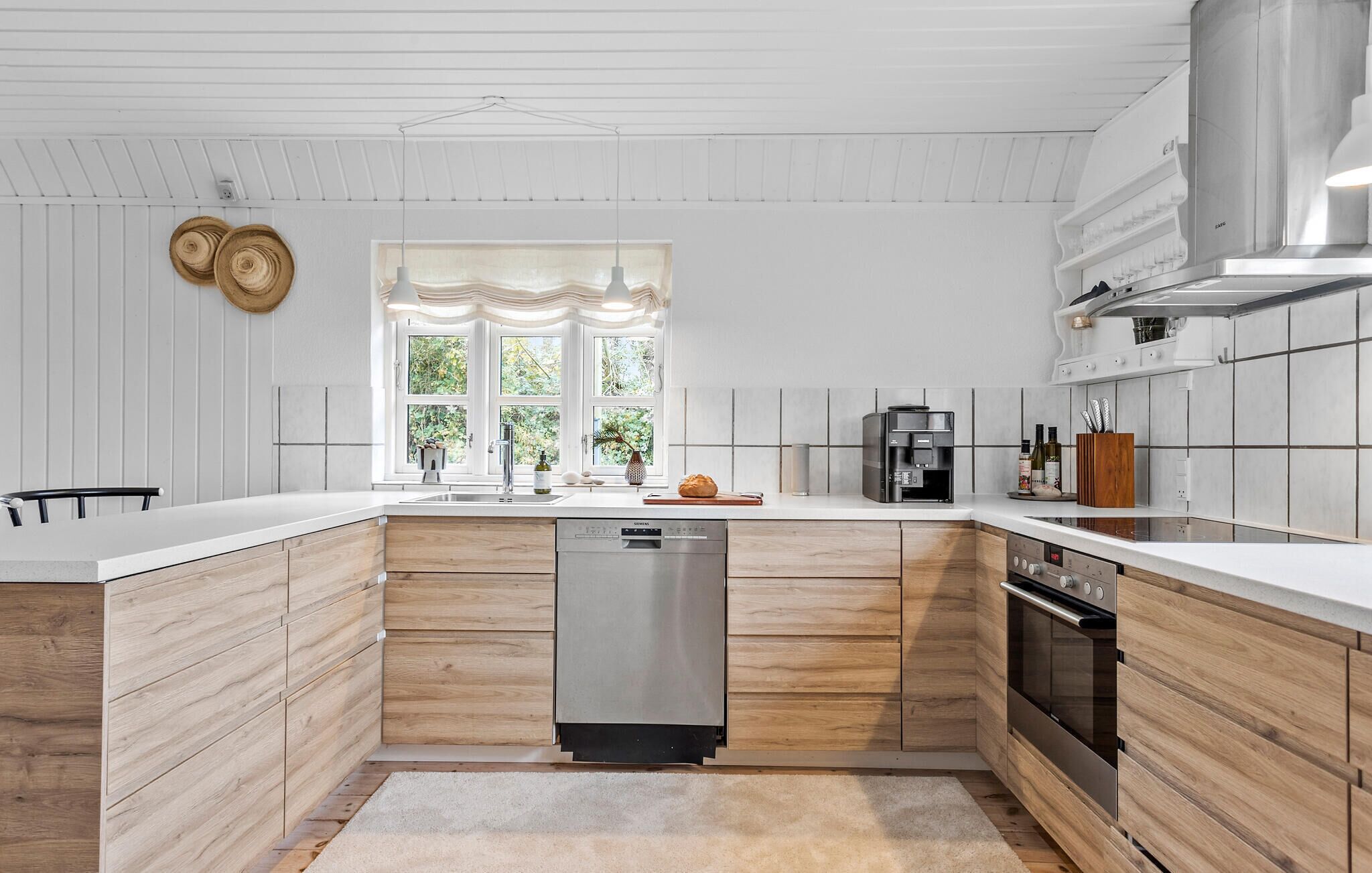 Eine moderne Küche mit Holzschränken, einem eingebauten Geschirrspüler und einer Kaffeemaschine.