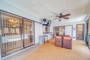 Relax in this spacious room with a sliding glass door leading to an outdoor area, a ceiling fan, and a comfortable seating area.