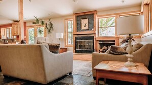 A cozy living room with two sofas, a fireplace, and a large window.