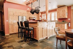 A kitchen with wooden cabinets, a central island, and a stone-tiled floor.