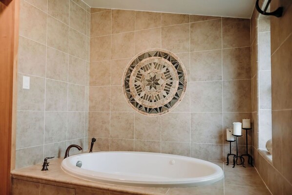Un baño con una bañera independiente, un muro de mosaico y un candelabro.