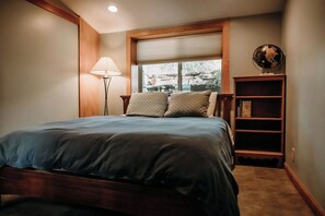 A bedroom with a bed, a lamp, a globe on a shelf, and a window with blinds.