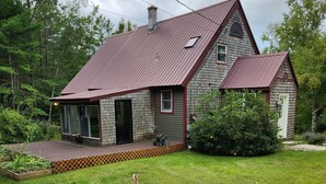 A two-story house with a red roof, a front porch, and a small attached garage.