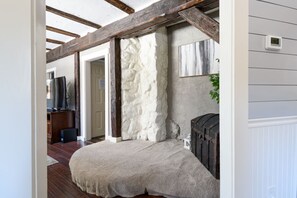 A room with a stone wall, wooden beams, a white door, and a small plant. - Every Season Get Away (Alexandria)