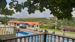 A pool area with a view of a house and surrounding landscape.