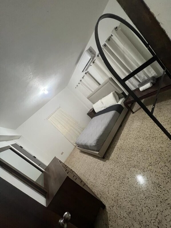 Habitación de hotel pequeña con una cama individual, un escritorio y una silla.