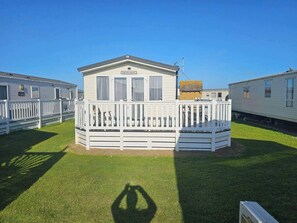 Een stacaravan met een omheind terras en een klein voortuintje, aangeduid als 'Porters Palace'.