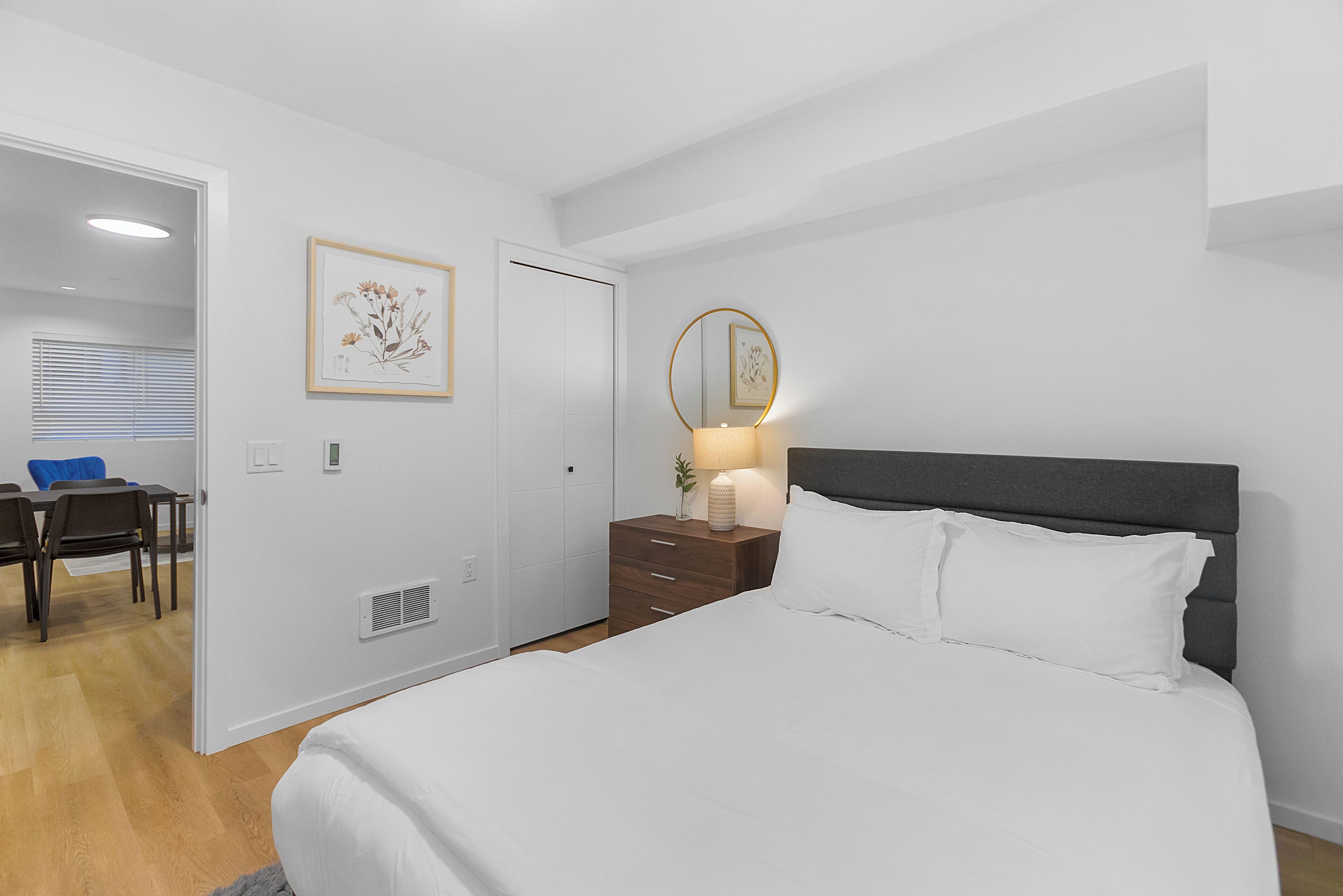 A bedroom with a bed, bedside table, lamp, and a framed picture on the wall.