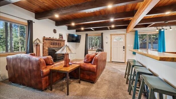 Una sala de estar acogedora con chimenea, sofás de cuero, una mesa de centro y una zona de bar con taburetes.