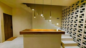 A modern kitchen with a central island, a staircase with integrated lighting, and a patterned wall. - Koom (Tulum)