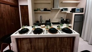 A modern kitchen with a central island, built-in appliances, and a minimalist design. - Koom (Tulum)