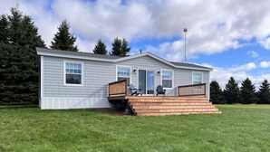 A single-story house with a covered deck, a front door, and a satellite dish.