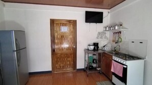 A compact kitchen with a refrigerator, stove, and a small countertop with kitchen appliances.