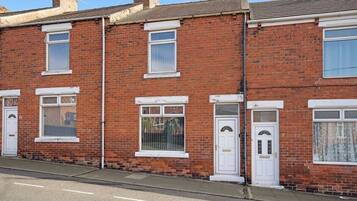 A row of red brick terraced houses with white-framed windows and doors.
