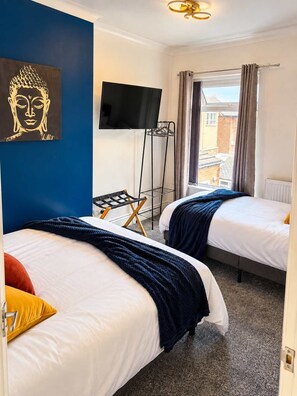 A hotel room with two beds, a flat-screen TV, a window with curtains, and a ceiling light fixture. - Chic 2BR Stay | Sleeps 6 | Close to Durham City (Ushaw Moor)
