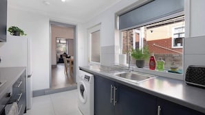 Una cocina moderna con lavadora integrada, ventana con vistas y encimera con fregadero.