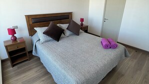 A neatly made bed with a patterned bedspread, two pillows, and a pair of rolled towels on the side. - Cozy fully equipped apartment in the center of Concepción. (Concepción)