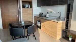 A compact kitchen with a central island, dark cabinetry, and a dining area with a table and chairs. - Cozy fully equipped apartment in the center of Concepción. (Concepción)