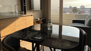 A modern kitchen with a dining area, a TV mounted above the counter, and a view of the city through a large window. - Cozy fully equipped apartment in the center of Concepción. (Concepción)