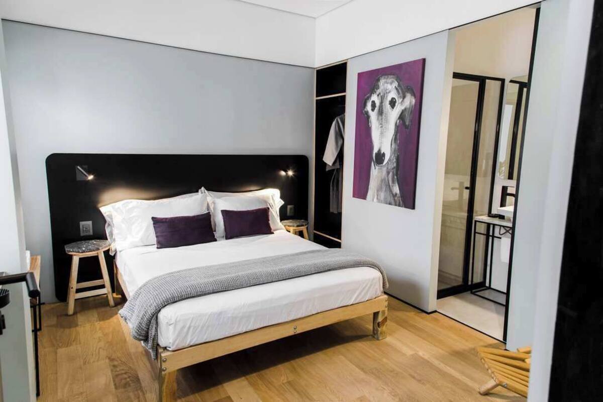 Une chambre à coucher moderne avec un grand lit, des tables de chevet, une armoire et un tableau au mur.