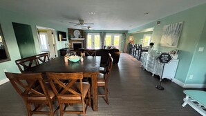 A spacious dining area with a long wooden table and chairs, a ceiling fan, and a sign on the wall. - Wine Country Oasis Pool/Sleeps 14 (Kerrville)