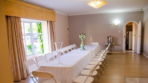 A conference room with a long table, chairs, a candelabra, and a chandelier. - The Advocate Suites Manor (Maseru)