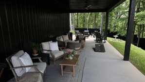 An outdoor covered patio with seating, a table, and a potted plant. - Creative Cabins - Hayloft (Logan)