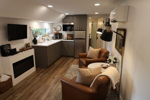 A modern kitchen with a flat-screen TV, built-in appliances, and a cozy seating area with a fireplace.