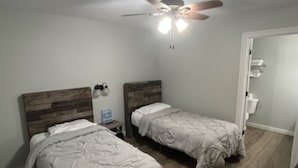 A bedroom with two beds, a ceiling fan, and a wooden floor.