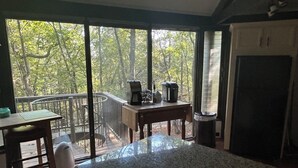 Una cocina con un ventanal grande, una cafetera y una mesa.