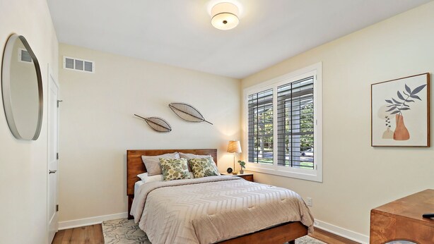 A bedroom with a wooden bed, a large mirror, a window with blinds, and a framed artwork on the wall. - The Bay Constellation -Walk to Yerkes |Firepit |Pool Table|New Construction (Williams Bay)