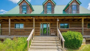 A log cabin with a porch, a front door, and a staircase leading to the entrance. - Hidden Falls Lodge | Hocking Hills, 93 Acres (New Straitsville)