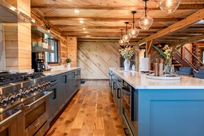 A modern kitchen with wooden beams, stainless steel appliances, and a central island with a vase of flowers.