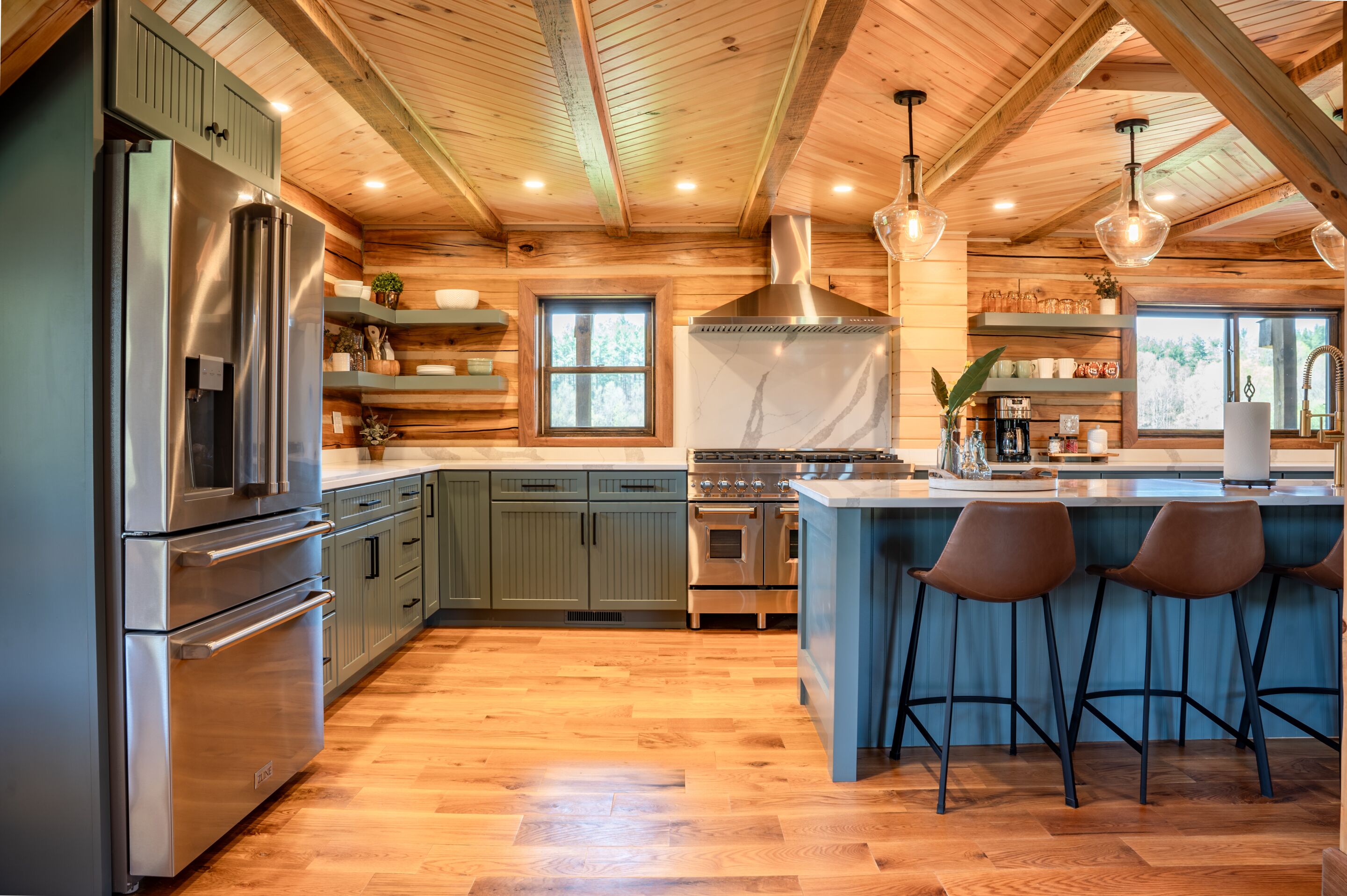 A modern kitchen with wooden beams, stainless steel appliances, and a central island with bar stools.