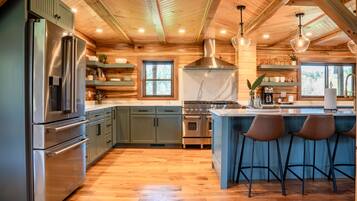 A modern kitchen with wooden beams, stainless steel appliances, and a central island with bar stools.
