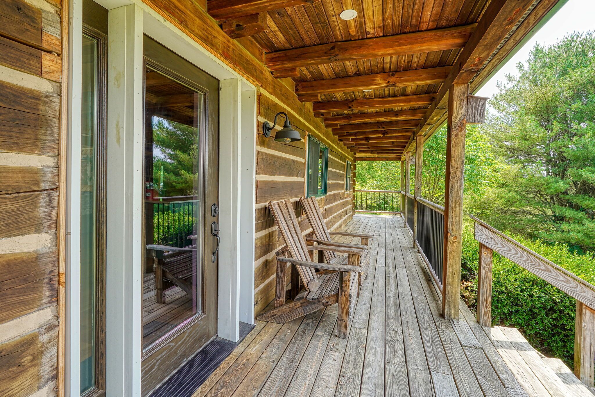 A wooden cabin with a covered porch, a bench, and a door with a glass panel.
