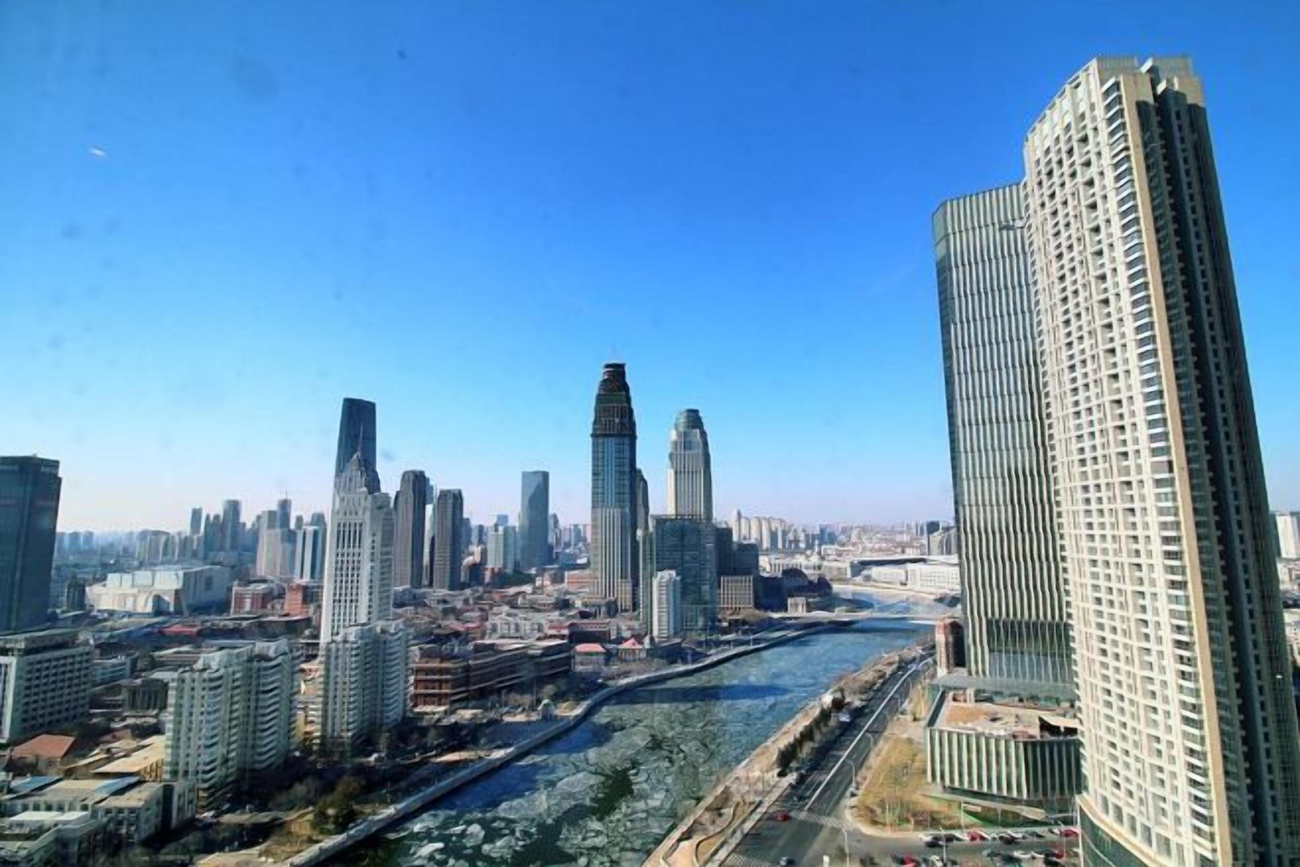 A cityscape with high-rise buildings, a river, and a clear sky.