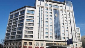 Ein mehrgeschossiges Hotel mit modernem architektonischen Design, gekennzeichnet durch eine markante Glasfassade und mehrere Balkone.