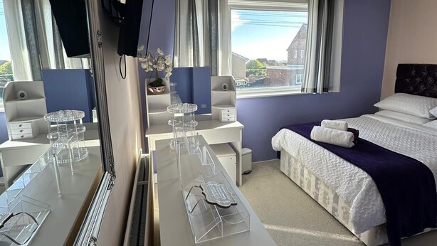 Een moderne hotelkamer met een groot bed, een bureau met spiegel, een kaptafel en uitzicht op het omliggende gebied.