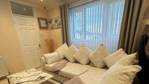 Een woonkamer met een bank, een salontafel en een gitaar.