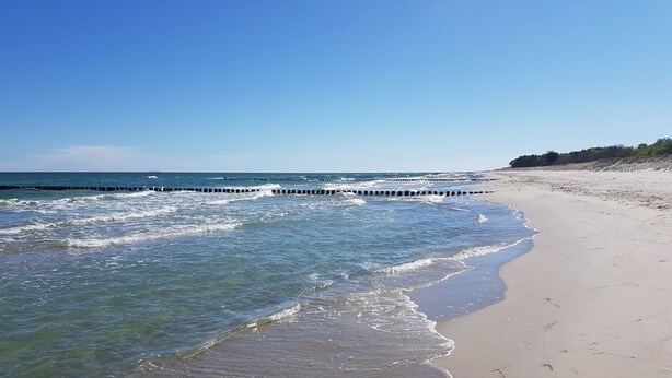 A sandy beach with gentle waves and a clear blue sky. - Haus Wellenrauschen - The vacation home "Wellenrauschen" the perfect place for peace and quiet (Zingst)