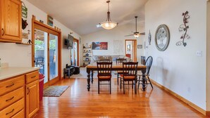 A spacious kitchen with wooden cabinets, a dining area with a wooden table and chairs, and a view of the outdoors through large sliding glass doors. - Sunrise Shores: Spectacular View! (Penn Yan)